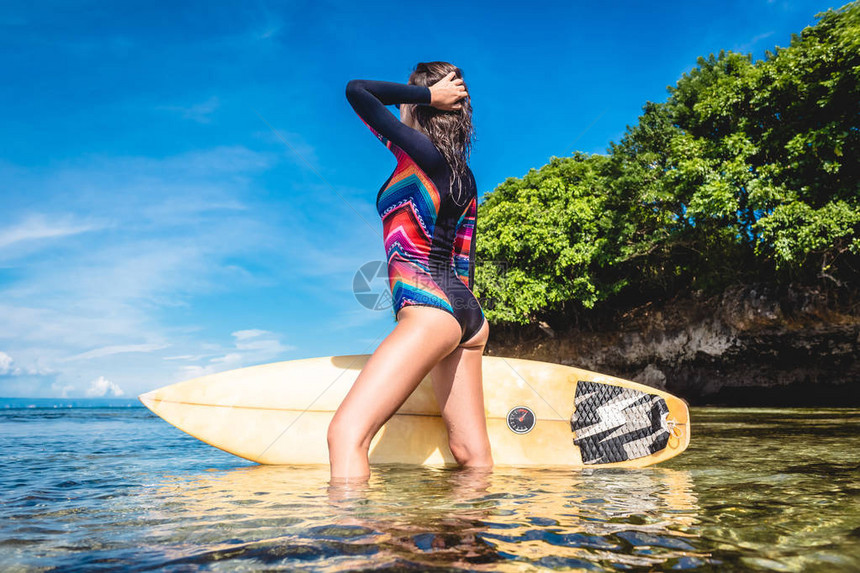 在印度尼西亚巴厘努沙杜阿海滩的海面上摆着冲浪板的妇女身穿湿衣图片