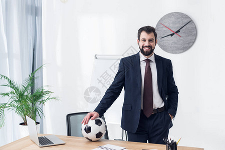 在办公室工作单位与足球赛一起微笑的生意人图片