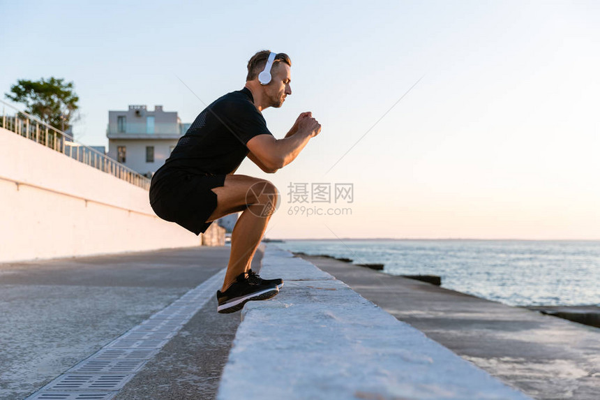 一边是运动型成年男子在耳机上跳在图片