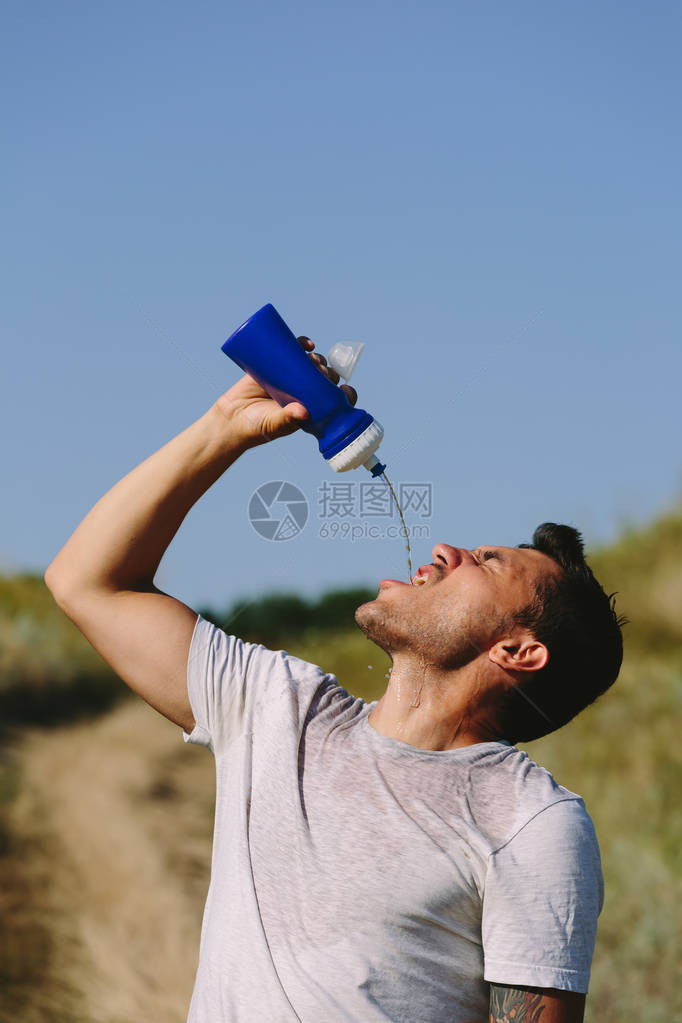 年轻人喝着贪婪的水从瓶子里拿来以自图片