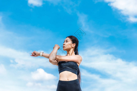 苗条的亚洲女运动员在多云的天空中伸手图片