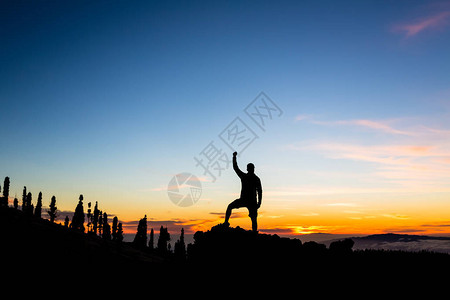 举手的越野跑者徒步旅行者或登山者在山顶上达到了一个目标图片