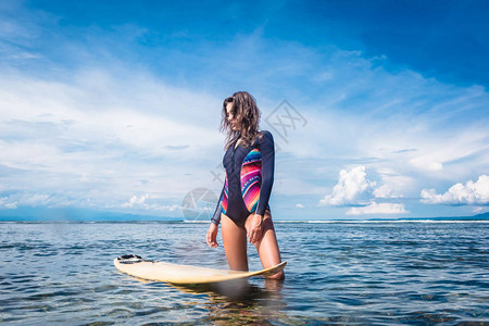 在印度尼西亚巴厘努沙杜阿海滩的海洋冲浪板上站立着身穿湿衣的图片