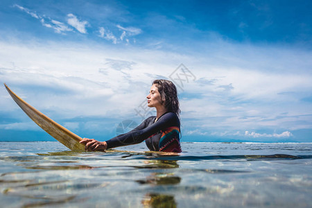印度尼西亚巴厘努沙杜阿海滩洋冲浪板上身穿湿衣的年轻女运动图片