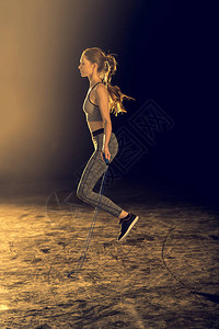 年轻的运动型女子用跳绳锻炼的侧视图图片