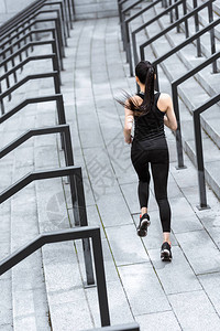 穿着运动服在体育场楼梯上奔跑的运动型年轻女子的背影图片