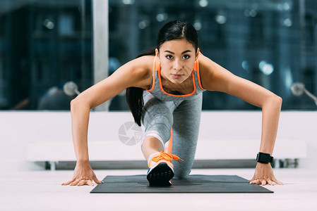 在体育中心健身垫上伸腿的女运动员在图片