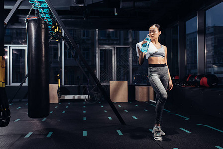 亚洲运动女孩拿着运动水壶在健身房里喝水图片