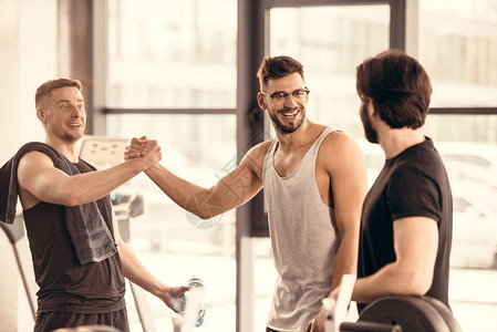 英俊的微笑运动员在健身房打招呼图片
