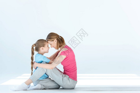 微笑的女儿和母亲在白色上互相拥抱图片
