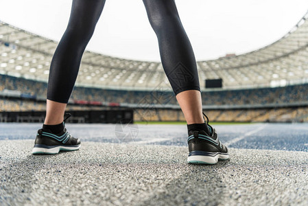 穿着运动鞋站在赛道体育场的年轻女运动员近距离图片