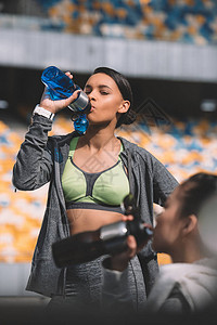 有吸引力的年轻运动女运动员从瓶中喝水背景图片