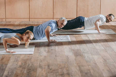 在培训课瑜伽垫子上与成年男子一起在瑜伽垫子图片