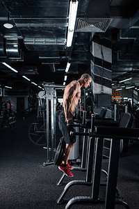 强壮的肌肉男在交叉健身房的不平等酒吧做俯卧撑图片
