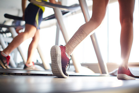 活跃的人在健身房的跑步机上跑步图片
