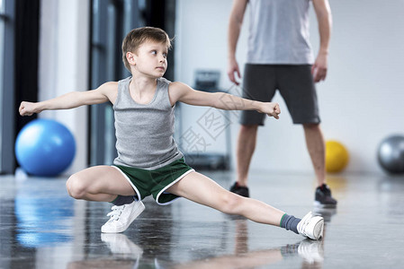 教练控制男孩在健身中心做伸展运动的教图片