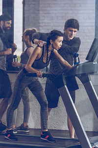 运动型年轻女运动员在健身房的跑步机上跑步图片