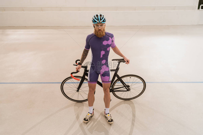 戴头盔骑自行车和看照相机的骑自行车运动员图片