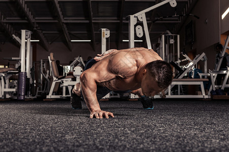 在健身房用一只手助力锻炼的肌肉人的图片