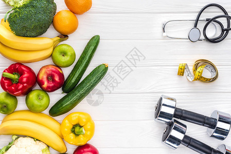 新鲜水果和蔬菜哑铃听诊器以及木制桌面上的测量胶背景图片