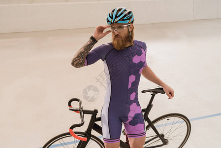 身着头盔的骑自行车运动员肖像在站自行车图片