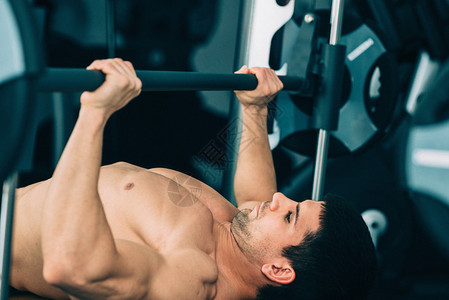 肌肉男举重躺在健身房的举重凳上图片