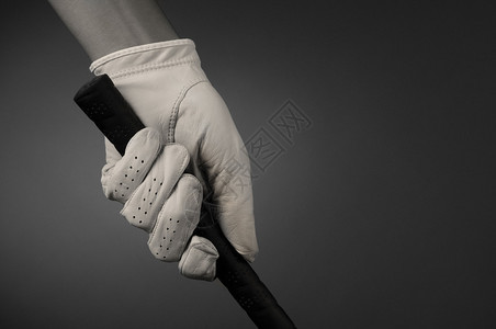 高尔夫球手的特写镜头手放在高尔夫球杆的把手上浅色或深色背景上的水平格式略带棕褐色调背景图片