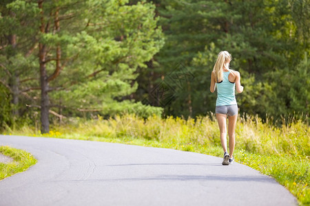 健康又健壮的金发女子在森林里跑步或走在路上图片