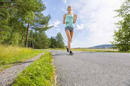 健康而快乐的金发女子在森林的一条路上跑步户外锻炼图片