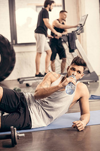 英俊的运动员在健身房用瓶子喝水图片