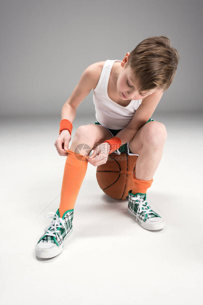男孩在运动服上坐着篮球图片