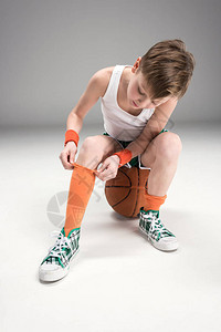 男孩在运动服上坐着篮球图片