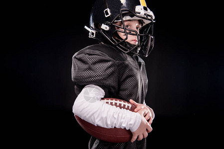 身穿制服的美国小足球运动员的侧边视角球在背景图片