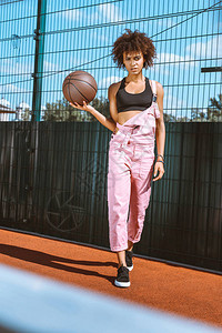 身穿运动胸罩和粉红色内衣手握篮球的年轻非图片