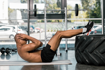AfricanAmerican男子在健身房健身垫上做腹图片