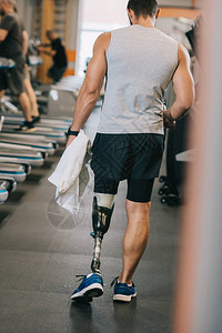 带假腿的运动员在健身房行走的后视图图片