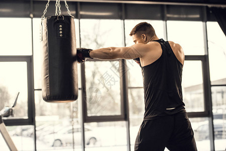 在健身房用拳击袋训练肌肉年轻图片