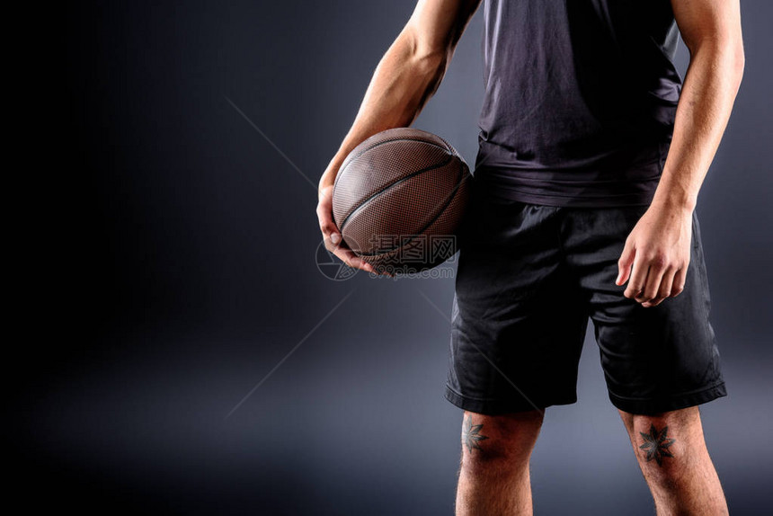 篮球运动员拿着黑色球的裁剪镜头图片