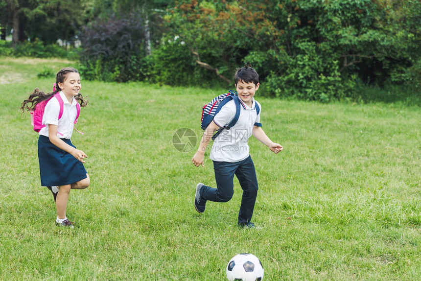 在公园草地上一起踢足球的学图片