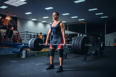 强壮的男举重员在健身房保持重杠铃的重量图片