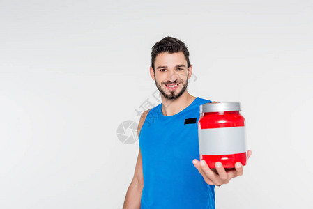 年轻英俊体育运动员手持运动补充品罐图片