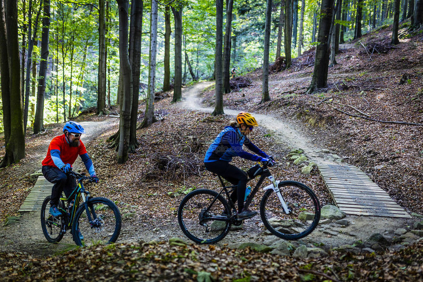 山地自行车妇女和男子在早春山区森林景观中骑自行车情侣骑自行车MTBenduro流径赛道图片