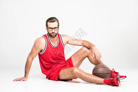 红运动服和眼镜中的篮球运动员与球坐在一起图片