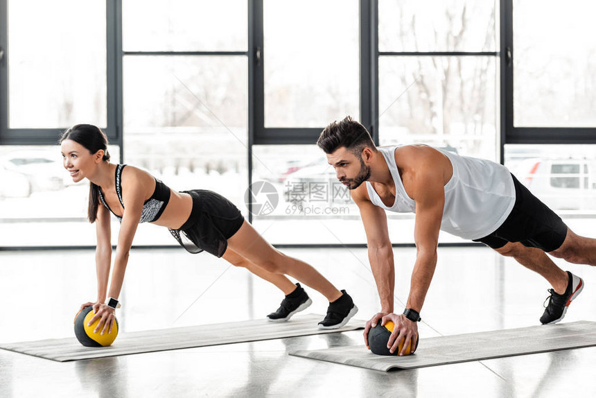 在瑜伽垫子上用药球锻炼运动的年轻运动夫妇图片