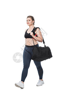 面带微笑的年轻体型加上带着运动包的女人走着背景图片