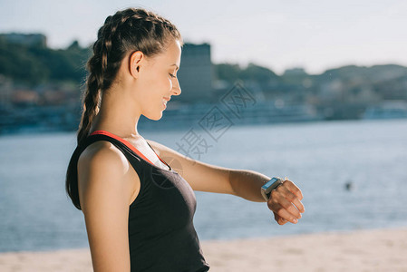 微笑的女运动员在海滩上看图片