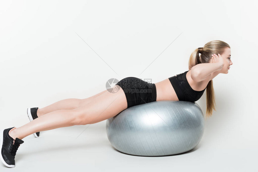 在白色隔离的健身球上锻炼的健身女人图片