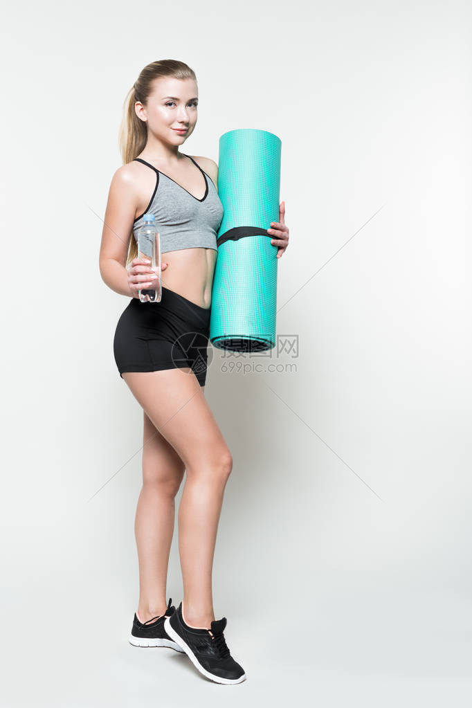 女运动员拿着水瓶和瑜伽垫被白色隔开图片