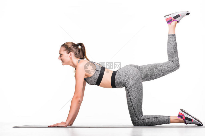 微笑的年轻女运动员在瑜伽垫上运动的一面图片