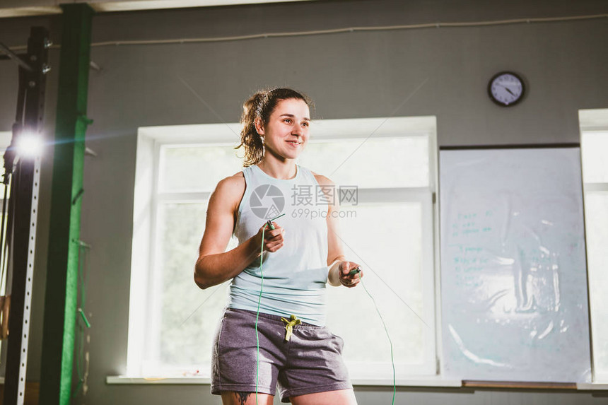 拿着跳绳的年轻白种人微笑的妇女健身房的健图片